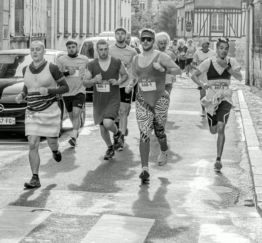 Participants in a fun run wearing various costumes on a city street. Energetic race scene.